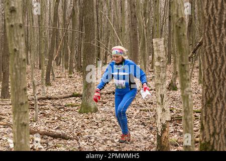 Grodno, Bielorussia - 25 Marzo, 2023: Donne caucasiche adulte in una foresta durante l'esercizio in Gro orienteering all'aperto Foto Stock