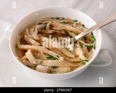 Zuppa austriaca di pancake a fette o Frittatensuppe con erba cipollina, un brodo di manzo trasparente Foto Stock