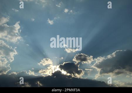 I raggi del sole che tramonta tra le nuvole Foto Stock