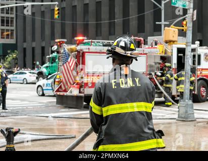 Fuoco poco profondo di un vigile del fuoco FDNY visto sulle strade di NYC, rispondendo a un'emergenza. NYPD può essere visto in background. Foto Stock