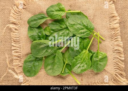 Foglie di spinaci verdi fresche su tessuto di iuta, macro, vista dall'alto. Foto Stock