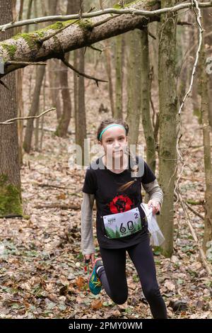 Grodno, Bielorussia - 25 marzo, 2023: Forte ragazza caucasica adolescente indossare abbigliamento sportivo che corre attraverso una foresta durante l'esercizio in esterni orienteering Gr Foto Stock