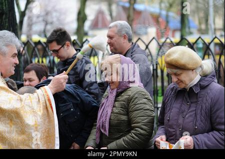 Lviv, Ucraina 15 aprile 2023. Un sacerdote ucraino benedice i credenti nella Chiesa dei SS. Olha ed Elisabetta, chiesa cattolica che celebrano la Pasqua per segnare la risurrezione di Gesù Cristo dai morti e la fondazione della fede cristiana. Foto Stock