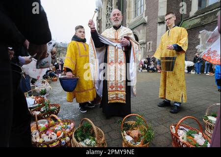 Lviv, Ucraina 15 aprile 2023. Un sacerdote ucraino benedice i credenti nella Chiesa dei SS. Olha ed Elisabetta, chiesa cattolica che celebrano la Pasqua per segnare la risurrezione di Gesù Cristo dai morti e la fondazione della fede cristiana. Foto Stock