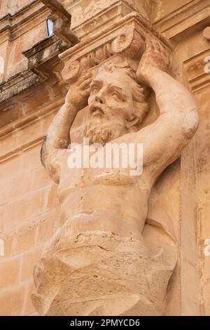 Mdina, Malta - 13 novembre 2022: Particolare della facciata del Museo della Cattedrale di San Paolo, un atlantico, figure maschili come lesene, statua di pietra calcarea che regge Foto Stock