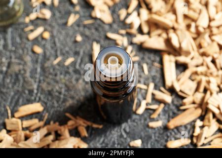 Bottiglia di olio essenziale con scaglie di legno di sandalo bianco su un tavolo Foto Stock