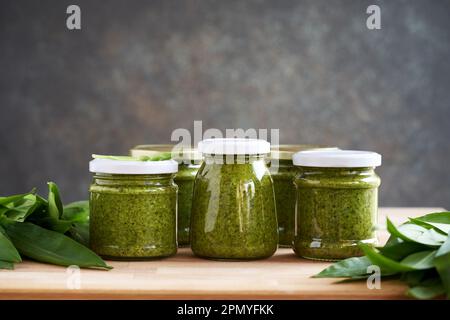 Vasetti di aglio selvatico verde conservato o pesto di allio ursinum con foglie fresche, con spazio copia Foto Stock