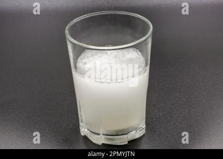 Sciogliendo le compresse effervescenti istantanee in un bicchiere d'acqua, il closeup è di colore nero Foto Stock