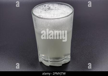 Sciogliendo le compresse effervescenti istantanee in un bicchiere d'acqua, il closeup è di colore nero Foto Stock