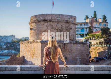 Donna turistica sullo sfondo della Torre Hidirlik di Antalya sullo sfondo della baia mediterranea dell'antico quartiere di Kaleici, Turchia Foto Stock