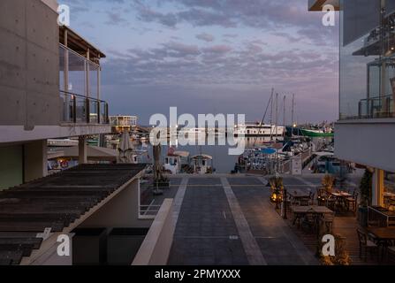 Limassol, Cipro - 23 marzo 2023 - Vista sul vecchio porto al crepuscolo con barche riflettenti, edifici e colorate luci notturne Foto Stock