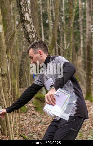 Grodno, Bielorussia - 25 Marzo, 2023: Uomo forte caucasico che indossa abbigliamento sportivo che corre attraverso una foresta durante l'esercizio in attività all'aperto orienteering Grodno Fore Foto Stock