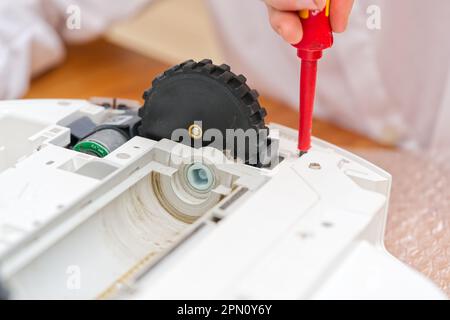 Addetto alla manutenzione, riparatore, manutenzione dell'aspirapolvere robotizzato. Riparazione del detergente robot. Foto Stock