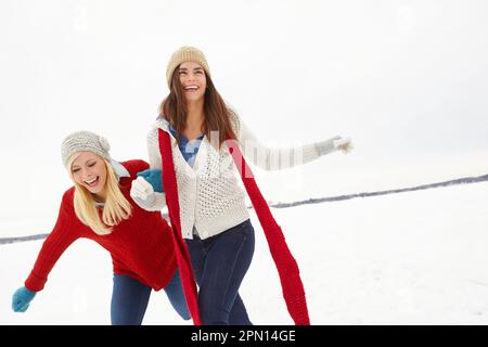 Dare una mano d'aiuto. due amici che corrono sulla neve insieme. Foto Stock