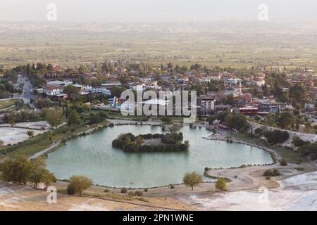 Lago minerale sullo sfondo del villaggio. Vista del villaggio di Pamukkale, Denizli, Turchia. Lago tra le rocce di Pamukkale Foto Stock