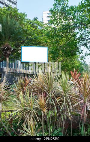 La tela per affissioni è un mockup su uno stand su una strada sullo sfondo verde della città Foto Stock