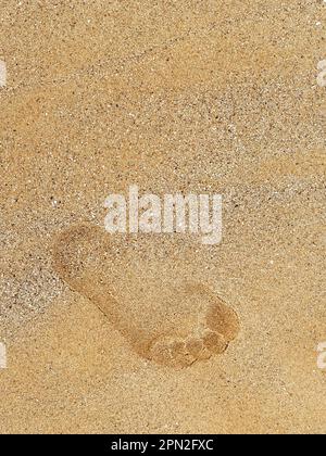 Lasciando l'impronta sulla sabbia. Ingombro in primo piano dal passaggio a piedi sulla spiaggia di sabbia, vista dall'alto con spazio copia, stile verticale. Viaggi in spiaggia, su Foto Stock