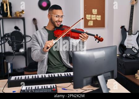 Un musicista afro-americano sorridente che suona il violino in uno studio musicale Foto Stock
