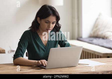 Donna armeno seria che lavora su un notebook a casa Foto Stock