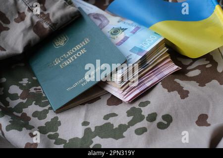 Carta d'identità militare Ucraina e hryvnia su uniforme militare. Pagamenti ai soldati dell'esercito ucraino, stipendi ai militari. Guerra in Ucraina Foto Stock