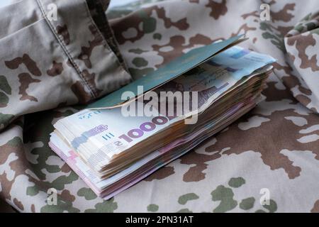 Carta d'identità militare Ucraina e hryvnia su uniforme militare. Pagamenti ai soldati dell'esercito ucraino, stipendi ai militari. Guerra in Ucraina Foto Stock