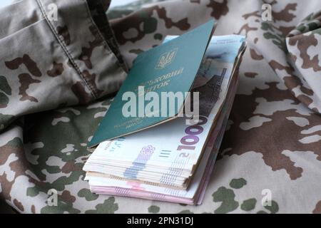 Carta d'identità militare Ucraina e hryvnia su uniforme militare. Pagamenti ai soldati dell'esercito ucraino, stipendi ai militari. Guerra in Ucraina Foto Stock