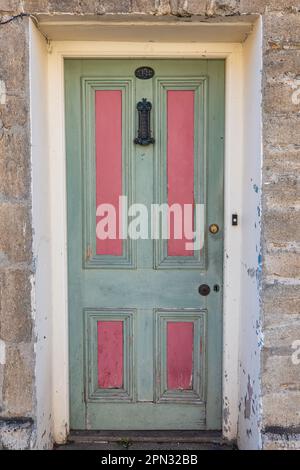 Rosa pastello e verde porta d'ingresso di un tradizionale cottage georgiano a Bridport, Dorset. Concetto porta tradizionale, cassetta di ferro e numero di casa. Foto Stock