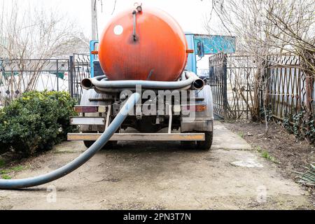 barile di camion di liquame che pompa fuori serbatoio settico in cortile di villaggio Foto Stock