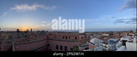 Marocco: Tramonto da un alto tetto, skyline di Marrakech, una delle città imperiali del Marocco situata a ovest delle colline pedemontane dell'Atlante Foto Stock