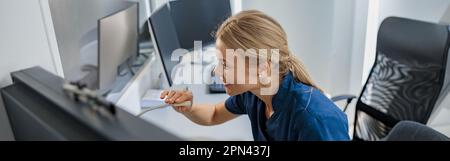 Nurse on Duty fa annuncio nel microfono al banco di ricevimento nella clinica moderna Foto Stock