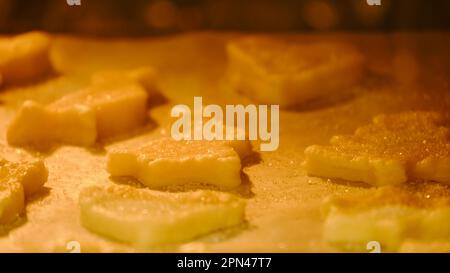 Processo di cottura dei biscotti dalla pasta sfoglia nel forno. Cucinare biscotti a forma di cuore, coniglietto pasquale e altri animali Foto Stock