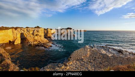 Il pittoresco paesaggio marino con scogliere, arco roccioso e pile (faraglioni), a Torre Sant'Andrea in luce del sole di mattina, mare Salentino costa, Puglia, Italia. Foto Stock