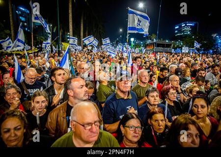 Netanya, Israele. 15th Apr, 2023. I manifestanti israeliani hanno bandiere durante una manifestazione anti-riforma a Netanya, a nord di Tel Aviv. Centinaia di migliaia di persone si sono radunate per la settimana diritta del sabato 15th contro i piani di revisione giudiziaria della coalizione di Netanyahu, un giorno dopo che l'agenzia di rating Moody's ha declassato le prospettive economiche di Israele da positive a stabili in mezzo alle proposte altamente controverse della coalizione di assestare la magistratura. Credit: SOPA Images Limited/Alamy Live News Foto Stock