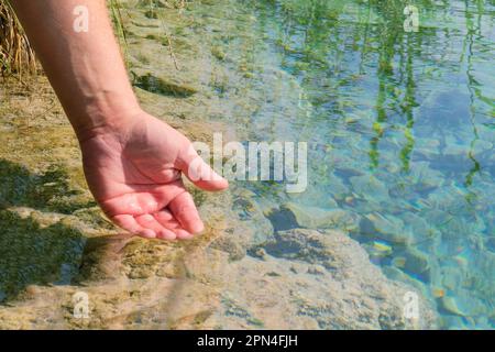 La mano umana tocca delicatamente la superficie dell'acqua nel fiume foresta o nel lago. Acqua pulita dal fiume. Foto Stock