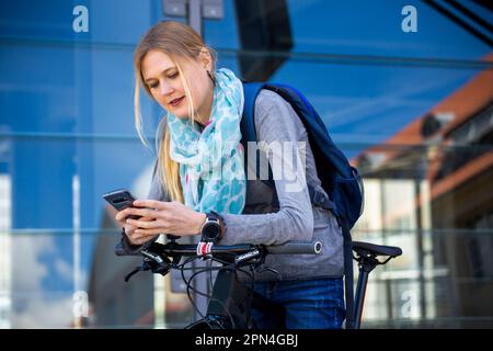 Giovane donna con la bicicletta in città Foto Stock