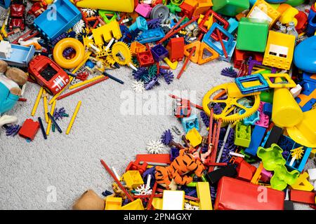 Un'abbondanza di giocattoli nella stanza dei bambini, molte parti multicolore di plastica dai progettisti, parti di ricambio per giocattoli, figurine e cubi. Foto Stock