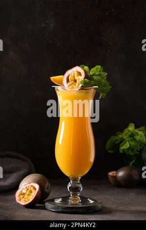 Frutto della passione e succo di mango in vetro di uragano su sfondo nero. Formato verticale. Bevanda tradizionale sana con mango. Freschezza lassi fatto di y Foto Stock