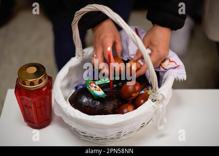 Una donna ortodossa mette le uova di Pasqua in un cesto dove saranno benedette dal sacerdote Igor Tatarintsev, in celebrazione della resurrezione di Cristo. Pasqua ortodossa celebrata in Francia, nella parrocchia ortodossa Madre di Dio e San Alessandro di Neva. I fedeli della Chiesa Ortodossa celebrano la risurrezione di Gesù Cristo, recandosi nella Chiesa per pregare i santi riti, portando cibo e bevande alla benedizione. E' l'atto più importante dei Riti Cristiani ortodossi. Foto Stock