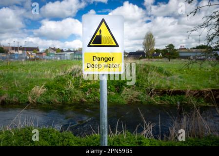 Pericolo segnale di avvertimento di acque profonde sulla riva rurale del fiume. Rischio di caduta e annegamento. Pericolo di slittamento. Foto Stock