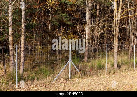 recinzioni metalliche nella foresta per proteggere il territorio dagli animali selvatici, recinzioni metalliche ai margini della foresta per proteggere la strada dagli animali selvatici Foto Stock