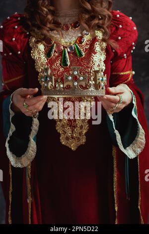 Primo piano sulla regina medievale in abito rosso con corona. Foto Stock