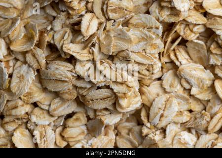 Versò una grande quantità di fiocchi di avena primo piano, sfondo di farina d'avena cruda cruda Foto Stock