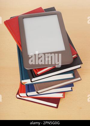 e-book o e-reader giacendo sulla cima di una pila di libri di copertina rigida Foto Stock