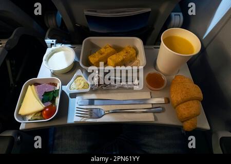 formaggi verdure frittata di pane e altri cibi sul tavolo pieghevole durante il volo in aereo di notte. Foto Stock