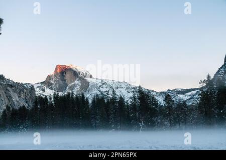 Mezza cupola, nel parco nazionale di Yosemite, cattura gli ultimi raggi del sole tramontato nel tardo pomeriggio invernale. Foto Stock