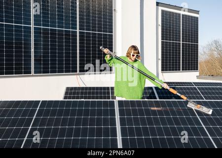 Donna lavaggio pannelli solari sul tetto Foto Stock