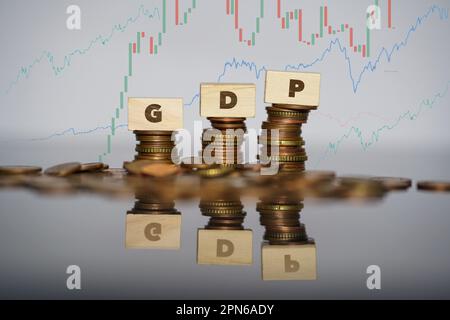 Concetto di prodotto interno lordo. Parola di GDP scritta su mattoni di legno su monete stack Foto Stock