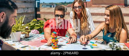 Gruppo di impiegati che giocano con una partita di jenga in terrazza Foto Stock