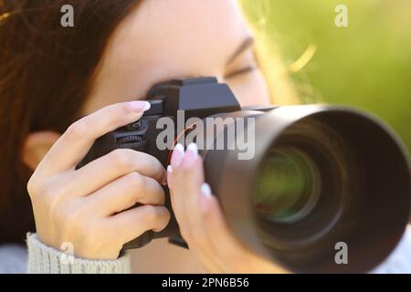 Primo piano ritratto di un fotografo che fotografa con fotocamera mirrorless sul verde Foto Stock