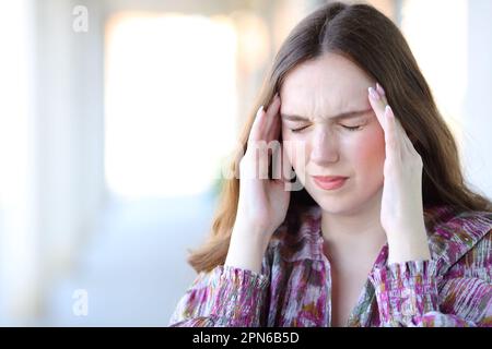 Donna stressata che soffre l'attacco di emicrania toccando il tempio nella strada Foto Stock